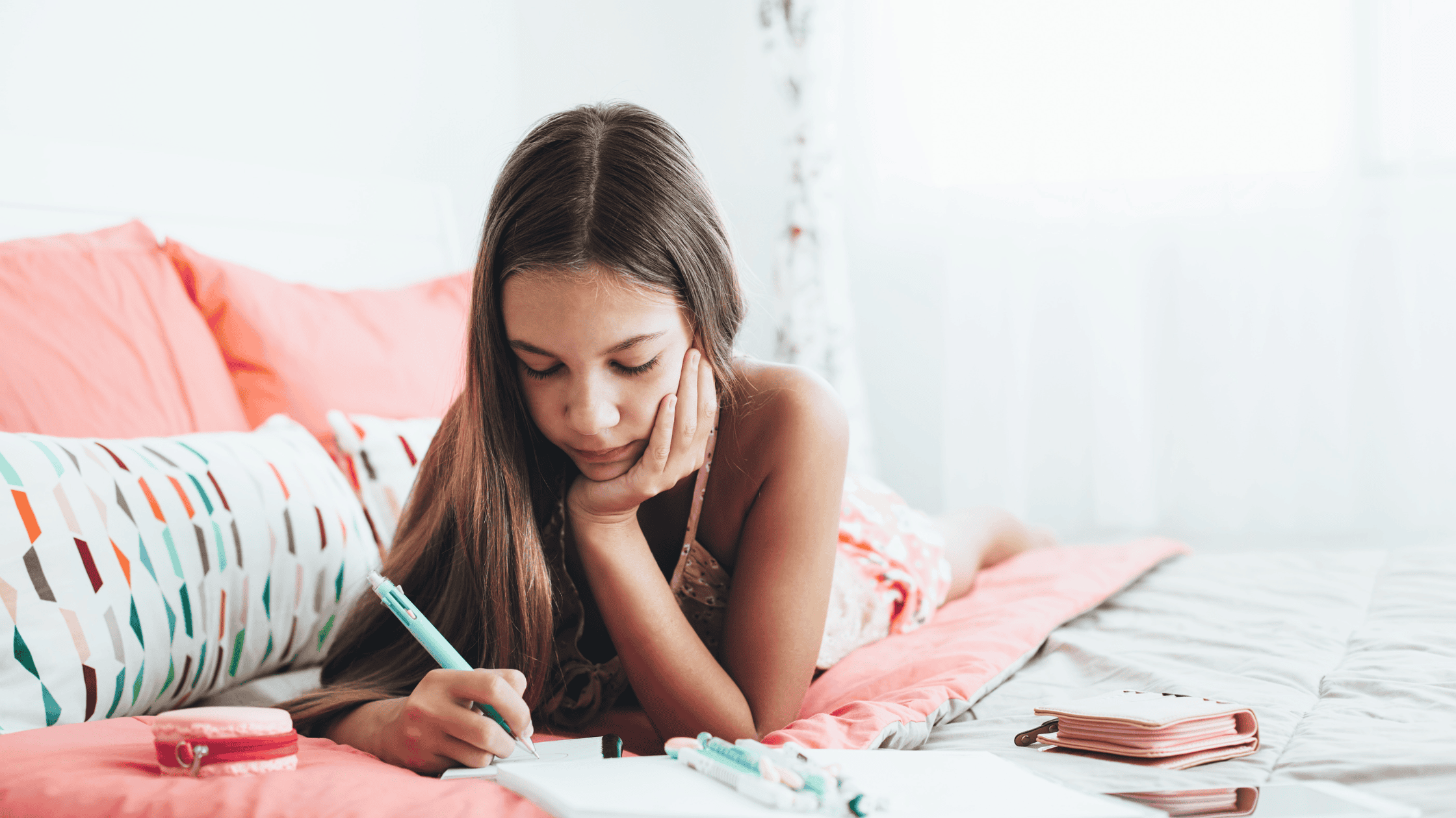 A young person sitting on a bed, holding a notebook, symbolizing reflection and the importance of consistency in foster care.